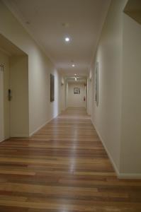 an empty hallway with wood floors and paintings on the walls at The Australian Hotel Motel in Dalby
