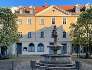 einen Brunnen vor einem großen Gebäude in der Unterkunft Pension Altstadt in Weimar