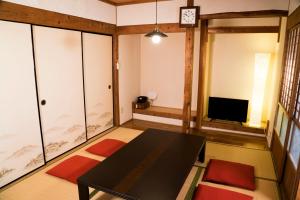 uma sala de estar com uma mesa preta e uma televisão em ゲストハウス ハルの家 em Amami