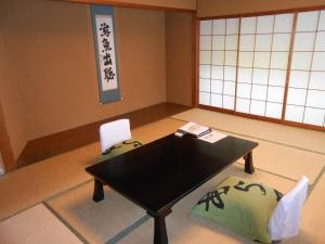 Habitación con mesa negra y 2 sillas en Arai Ryokan, en Izu