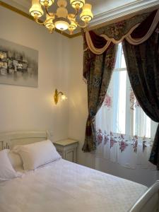 1 dormitorio con cama, lámpara de araña y ventana en Appartement Maison de L'Église du Couvent, en Narbona