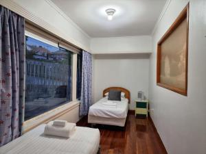 Habitación pequeña con 2 camas y ventana en Cozy 3BR Mt Roskill - Heat Pump & Wifi & Netflix en Auckland
