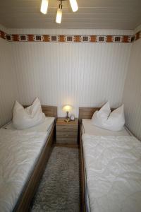 - 2 lits dans une petite chambre avec une lampe sur une table dans l'établissement Steinwarder 35-37 SB5 012 Steinwarder 35-37, à Heiligenhafen