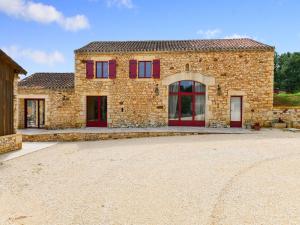 Casa de piedra con puertas rojas y entrada en Majestic holiday home with swimming pool, en Prats-du-Périgord