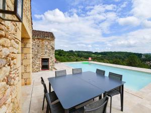 una mesa y sillas en un patio con piscina en Majestic holiday home with swimming pool, en Prats-du-Périgord