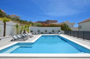 a swimming pool with lounge chairs next to a fence at Apartments Vrania in Seget Vranjica