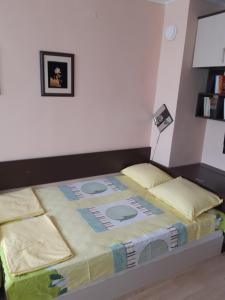 a bedroom with a large bed with a blanket on it at Самостоятелен апартамент на брега на морето Обзор in Obzor