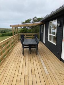 una terraza de madera con una mesa y un banco. en Gl. Klitgaard Camping & Cottages, en Løkken