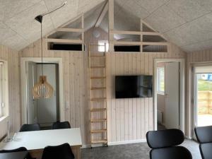 a room with a loft bed with a desk and chairs at Gl. Klitgaard Camping & Cottages in Løkken