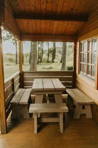 a porch with two picnic tables in a cabin at Atpūtas kempings Usma in Usma