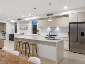 a kitchen with white cabinets and a kitchen island with bar stools at Nautilus Ocean Breeze in Kingscliff