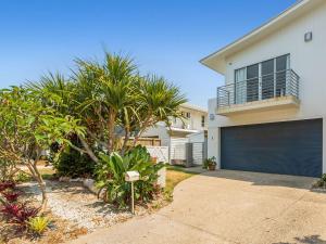 ein weißes Haus mit Garagentor und Palmen in der Unterkunft Casuarina Dreaming Townhouse with Pool in Kingscliff