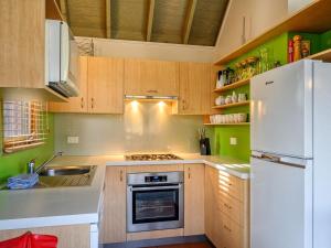 cocina con armarios de madera y nevera blanca en Banjo Apartments en Thredbo