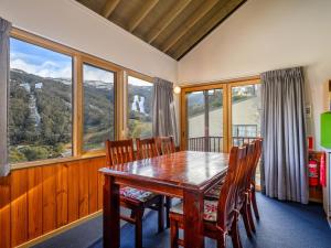 a dining room with a table and chairs and windows at Banjo Apartments in Thredbo