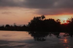 a sunset over a pool with a reflection in the water at Casa Costa Suites in Kanali
