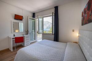 een slaapkamer met een bed, een bureau en een raam bij Hotel Al Molino in Malcesine