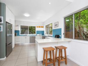 a kitchen with a white counter and two stools at Beach House on Pearl - Kingscliff Central in Kingscliff