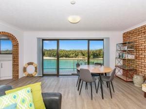 a living room with a table and chairs and a balcony at Creekfront Kingscliff Waters 2 in Kingscliff
