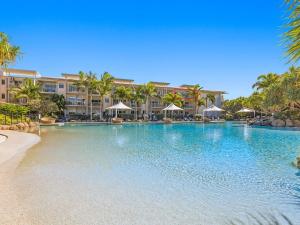 a large swimming pool with palm trees and buildings at Resort & Spa 6316 with resort Tropical Pool in Kingscliff