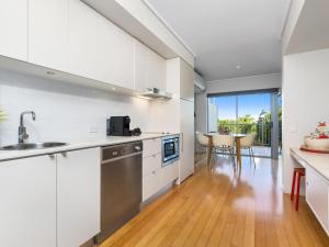 a kitchen with white cabinets and a table with chairs at Resort & Spa 6316 with resort Tropical Pool in Kingscliff