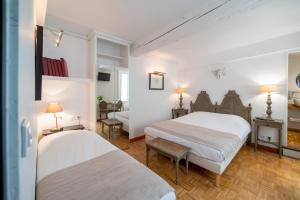 two beds in a room with white walls and wooden floors at Logis - Hotel De La Mairie in Embrun