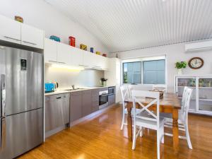 a kitchen with a wooden table and white appliances at Casuarina Beach Shacks 10 with Pool in Kingscliff