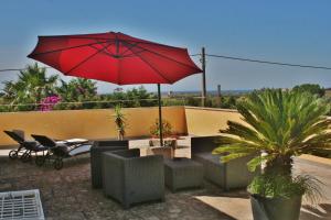 une terrasse avec un parasol rouge, des chaises et une table dans l'établissement Vacanze in Puglia, à San Pietro in Bevagna