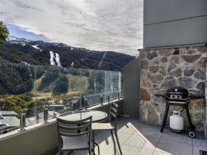 a balcony with a table and chairs and a grill at Lantern 1 Bedroom Deluxe with hot tub and car park in Thredbo