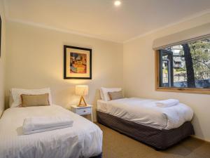 two beds in a room with a window at Lhotsky 2 Bedroom apartment with balcony mountain views and BBQ in Thredbo