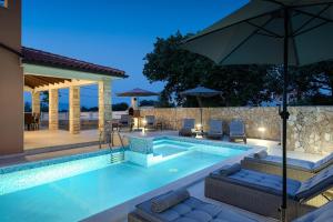 uma piscina com cadeiras e um guarda-sol em Villa Gloria, villa with heated pool em Kavran