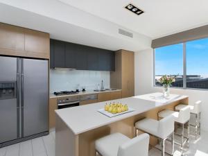 a kitchen with a large island with chairs and a counter top at 1328 Luxury Beachfront Penthouse with Heated Rooftop Jacuzzi in Kingscliff