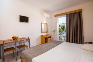 a hotel room with a bed and a desk and a window at Dias Studios & Suites in Faliraki