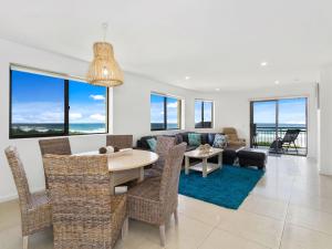 a dining room and living room with a table and chairs at Shoreline 9 Penthouse With Ocean Views in Hastings Point