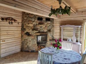 a dining room with a table and a stone fireplace at Sodyba Atgaiva in Lazdininkai