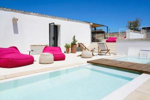 una piscina con sillas rosas en un patio en Palazzo De Noha - Boutique Hotel, en Lecce