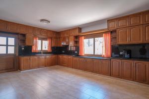 an empty kitchen with wooden cabinets and windows at Andrea Villa by Prestige Bookings in Peyia