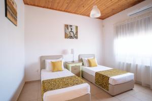two beds in a room with a window at Andrea Villa by Prestige Bookings in Peyia +23 photos