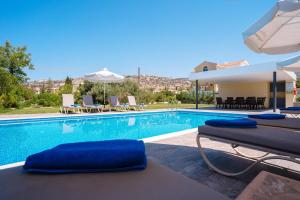 a swimming pool with lounge chairs and a villa at Andrea Villa by Prestige Bookings in Peyia