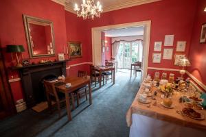 uma sala de jantar com paredes e mesas vermelhas e uma lareira em Homelands Guest House em Barnard Castle