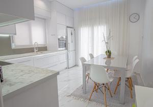 uma cozinha branca com uma mesa e cadeiras brancas em Luxury Apt 115m2 em Atenas