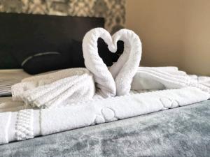 a pile of towels and towel swans on a bed at The Eastleigh in Skegness