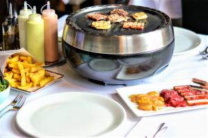 a table with plates of food and a grill at Alpine Hotel by SnowWorld in Landgraaf