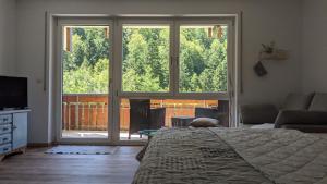 ein Schlafzimmer mit einem Bett und einem großen Fenster in der Unterkunft SonnenStrahl in Todtmoos