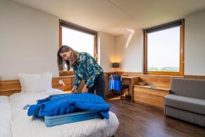 a woman is making a bed in a hotel room at Alpine Hotel by SnowWorld in Landgraaf