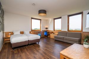 a bedroom with a bed and a couch and a table at Alpine Hotel by SnowWorld in Landgraaf