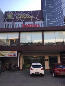 a white car parked in a parking lot in front of a building at RedDoorz Plus @ Hotel Alden Makassar in Makassar