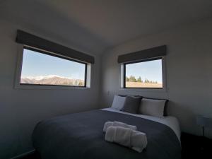a bedroom with a large bed with two windows at Skyrim Lodge in Lake Tekapo