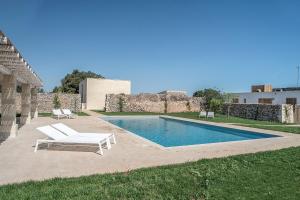 a large white swimming pool sitting in front of a building at Masseria Berzario in Melendugno