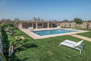 a swimming pool in a yard with two chairs and a table at Masseria Berzario in Melendugno