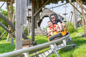 a man and a child riding on a roller coaster at Alpine Hotel by SnowWorld in Landgraaf